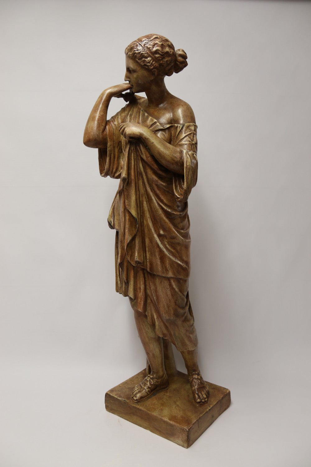 A nineteenth-century Neoclassical sculpture depicting Diana the Huntress draped in classical robes standing on a square base with a warm beige patinated finish. View III