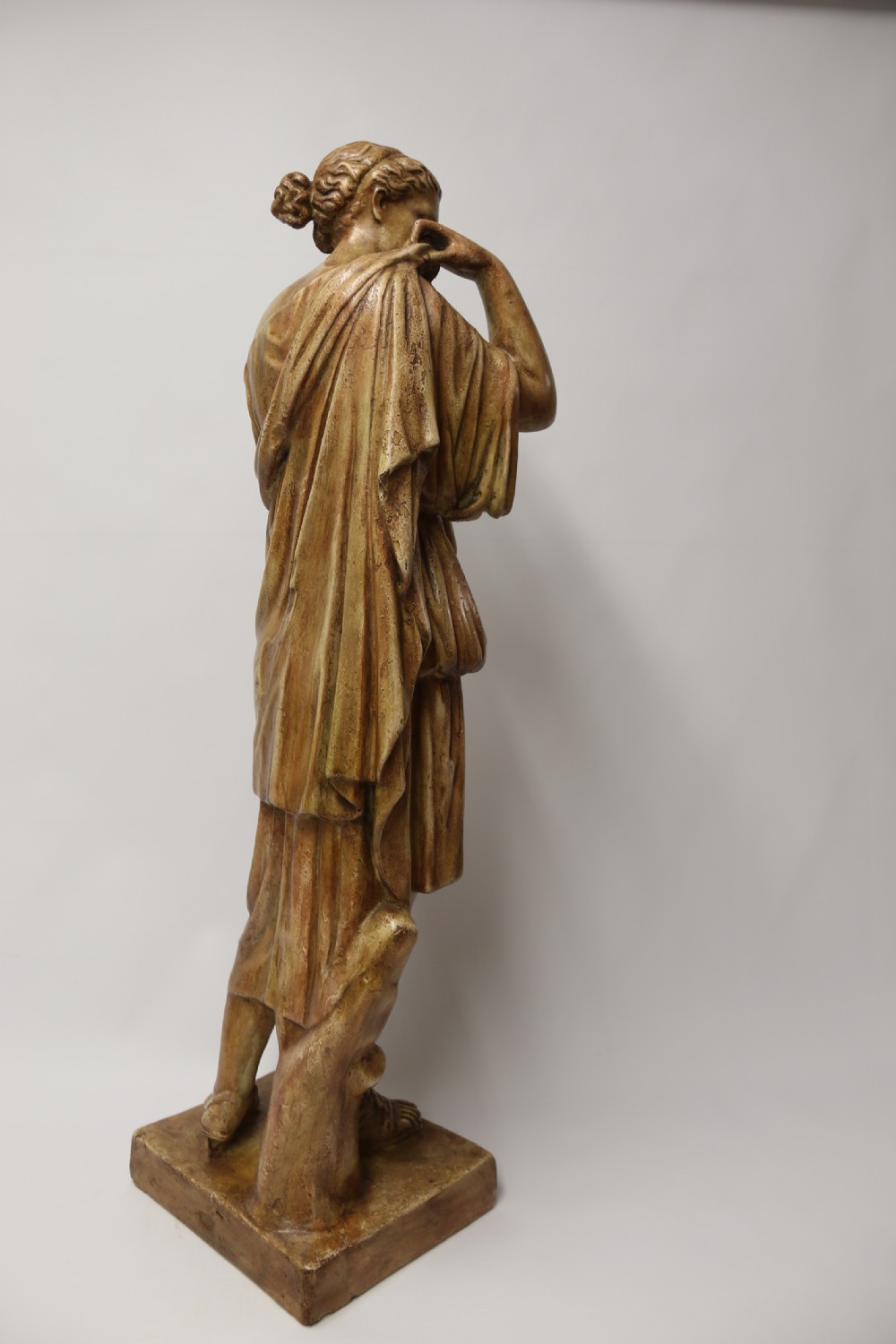 A nineteenth-century Neoclassical sculpture depicting Diana the Huntress draped in classical robes standing on a square base with a warm beige patinated finish. View V