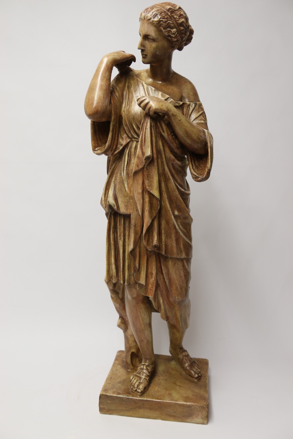 A nineteenth-century Neoclassical sculpture depicting Diana the Huntress draped in classical robes standing on a square base with a warm beige patinated finish. View VIII