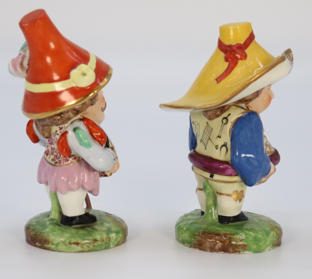 A pair of 19th-century hand-painted Samson porcelain Mansion House dwarf figurines featuring oversized hats and patterned waistcoats. View IX