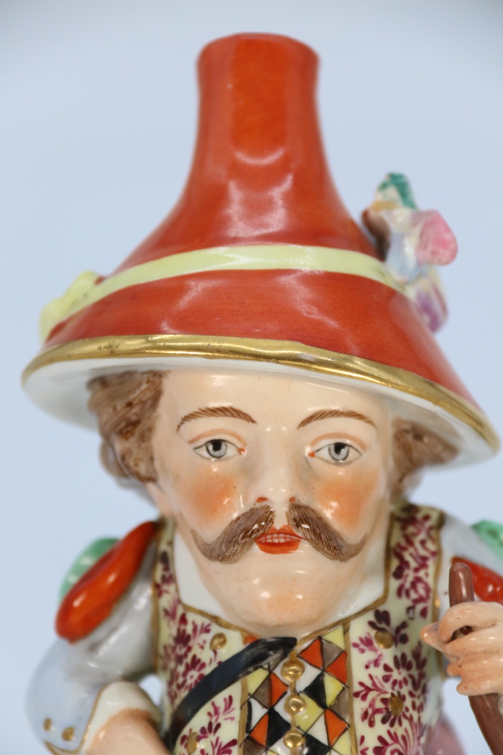 A pair of 19th-century hand-painted Samson porcelain Mansion House dwarf figurines featuring oversized hats and patterned waistcoats. View XXIX