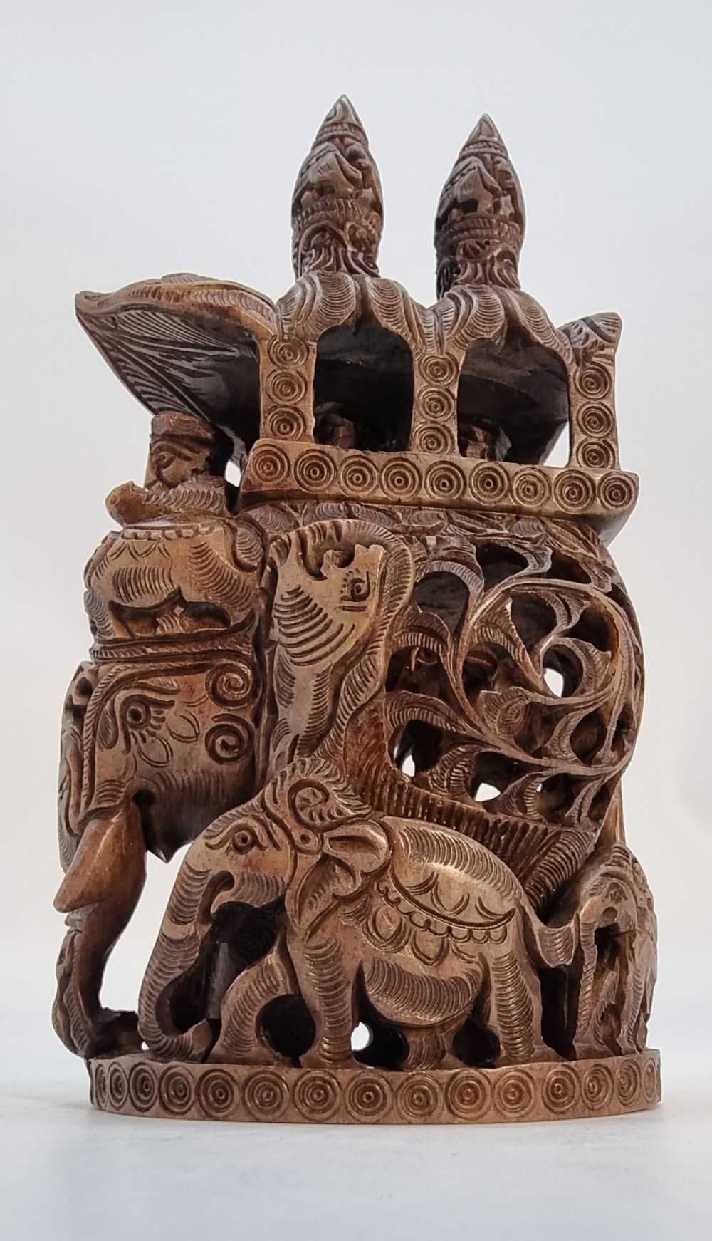 An intricately hand-carved brown soapstone sculpture featuring a ceremonial elephant carrying an elaborate howdah with pierced lattice detailing.