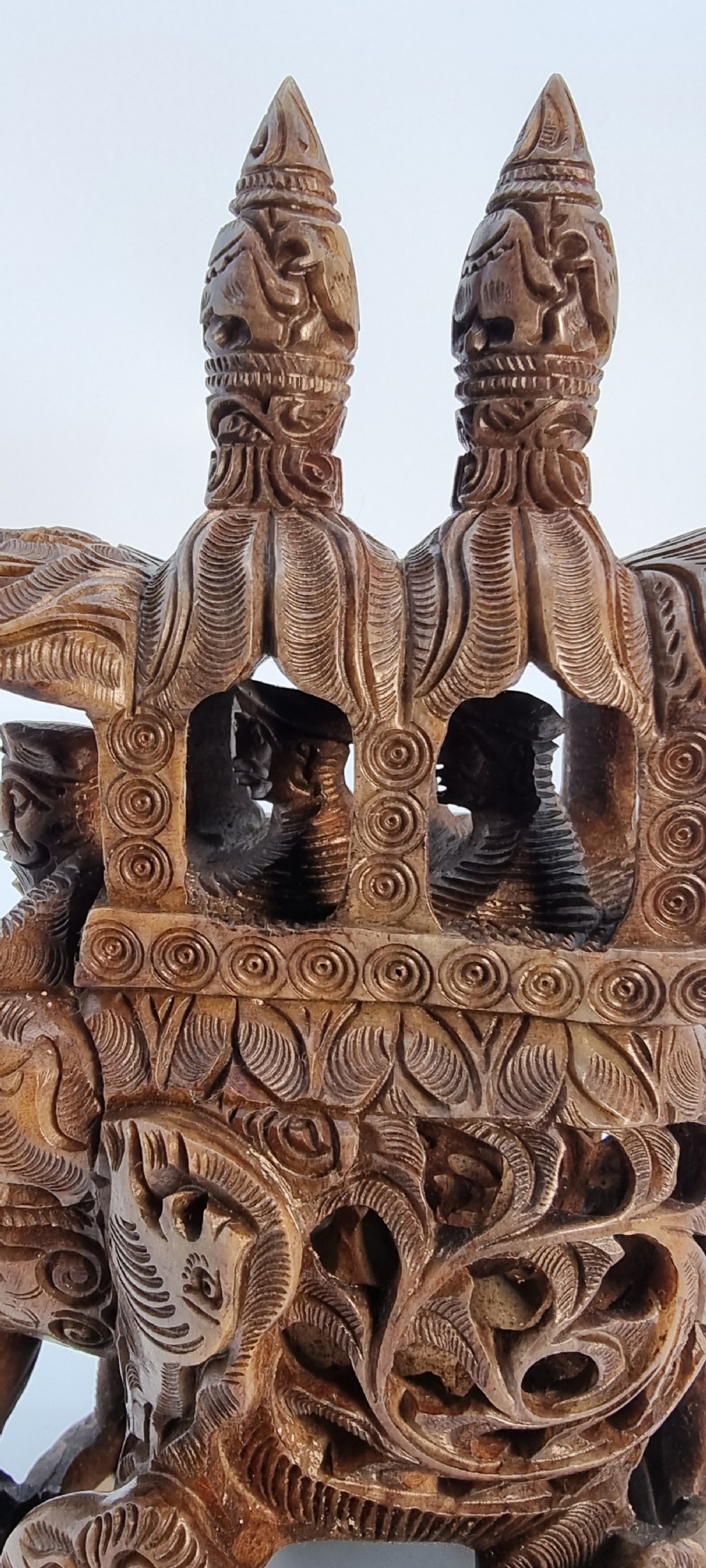 An intricately hand-carved brown soapstone sculpture featuring a ceremonial elephant carrying an elaborate howdah with pierced lattice detailing. View II