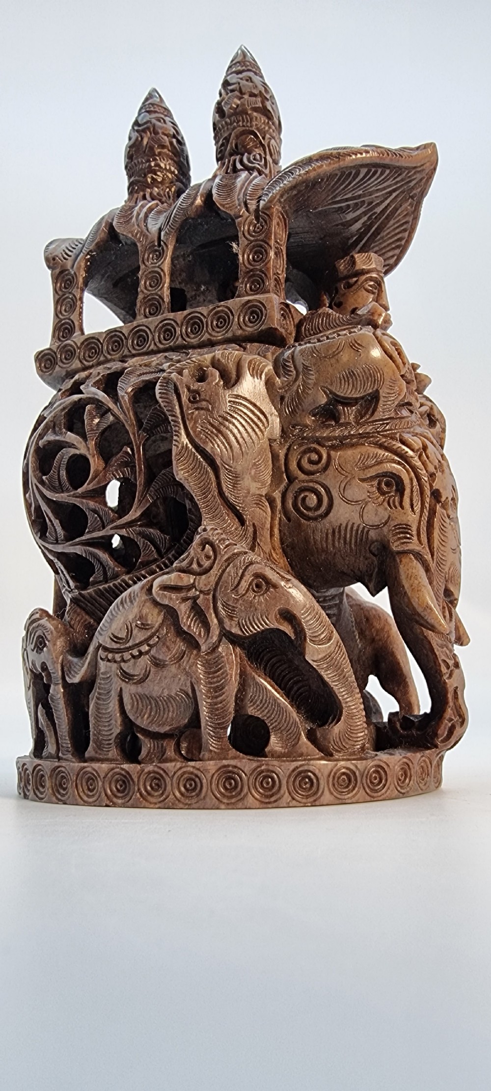 An intricately hand-carved brown soapstone sculpture featuring a ceremonial elephant carrying an elaborate howdah with pierced lattice detailing. View XII