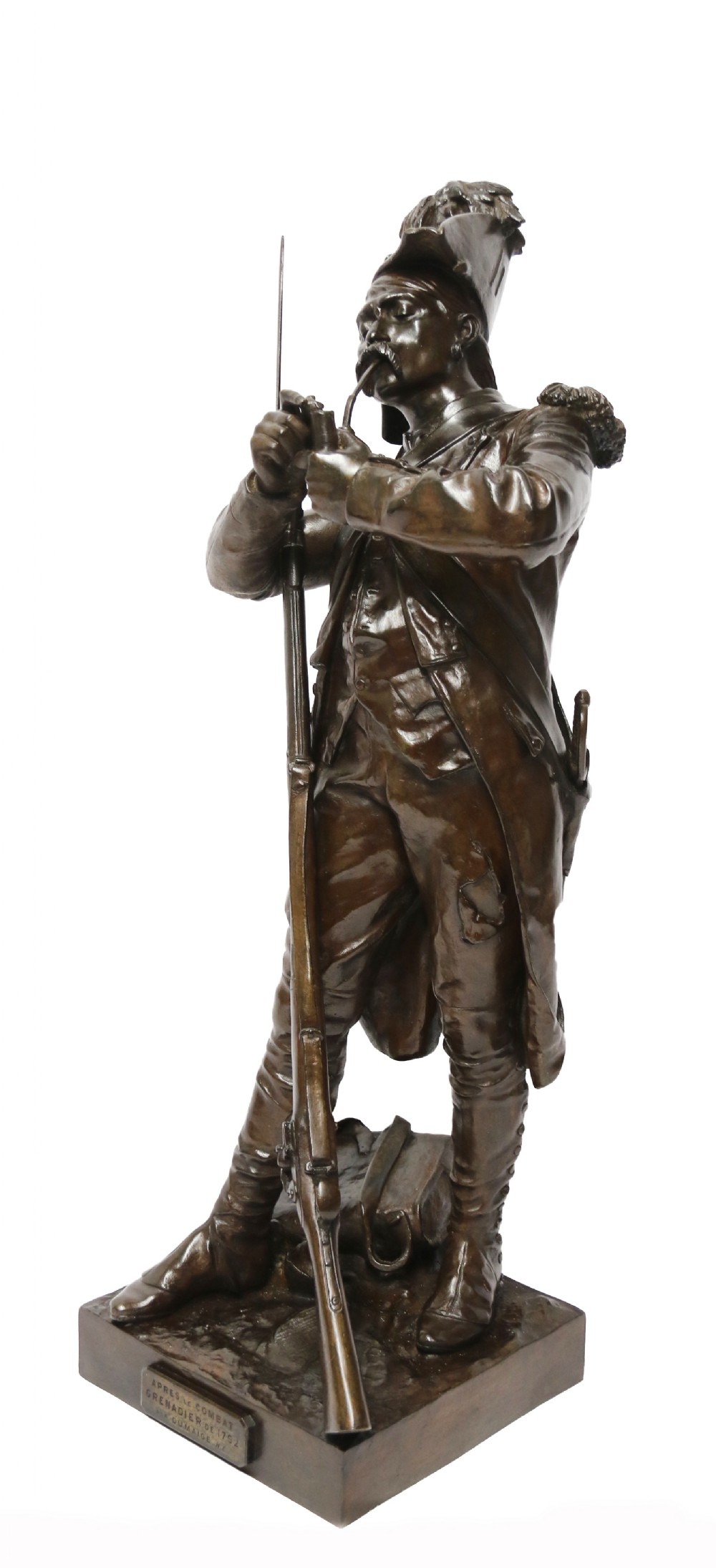 A dark brown patinated bronze sculpture depicting a 1792 French grenadier soldier in full uniform lighting a pipe beside a rifle.