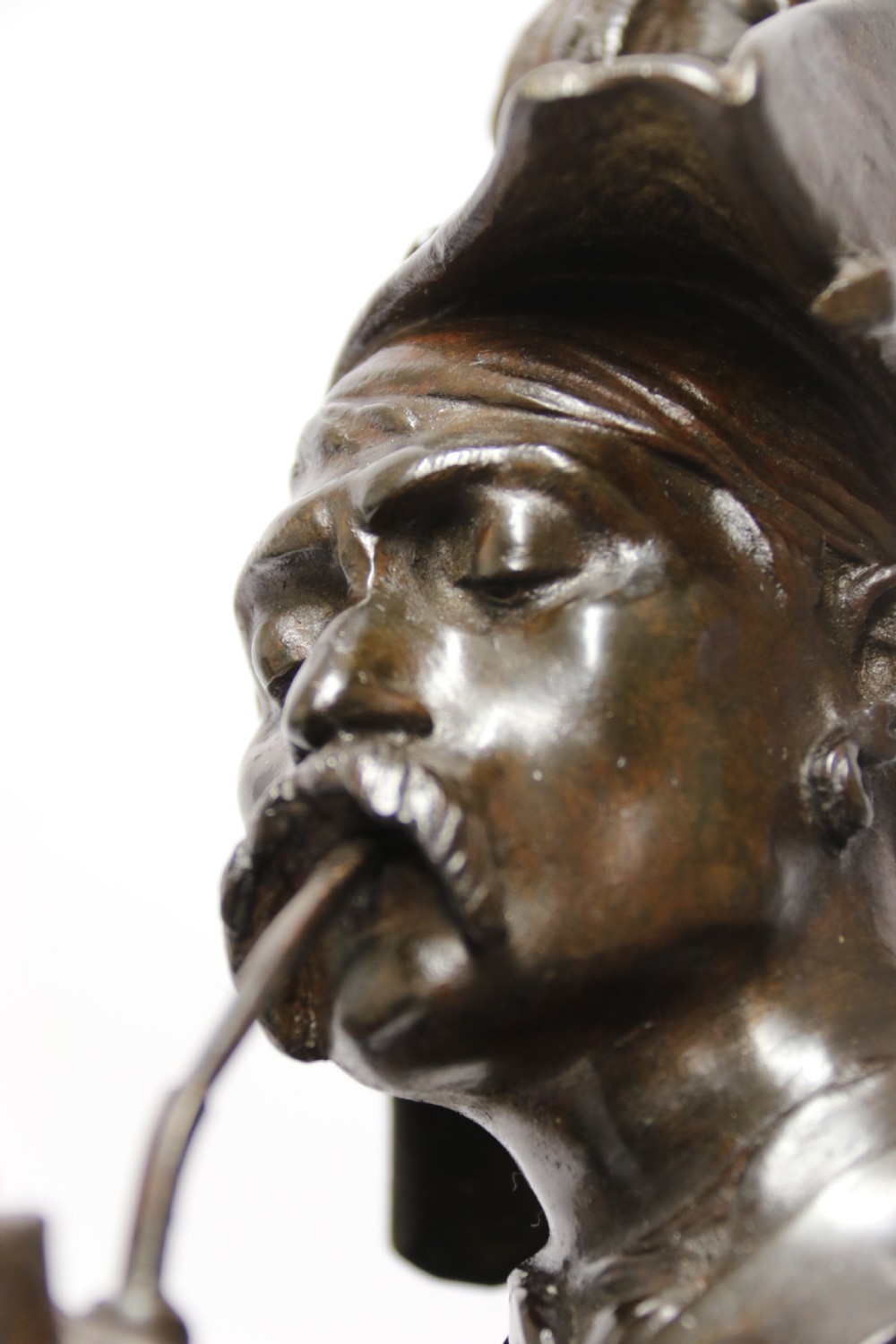 A dark brown patinated bronze sculpture depicting a 1792 French grenadier soldier in full uniform lighting a pipe beside a rifle. View X