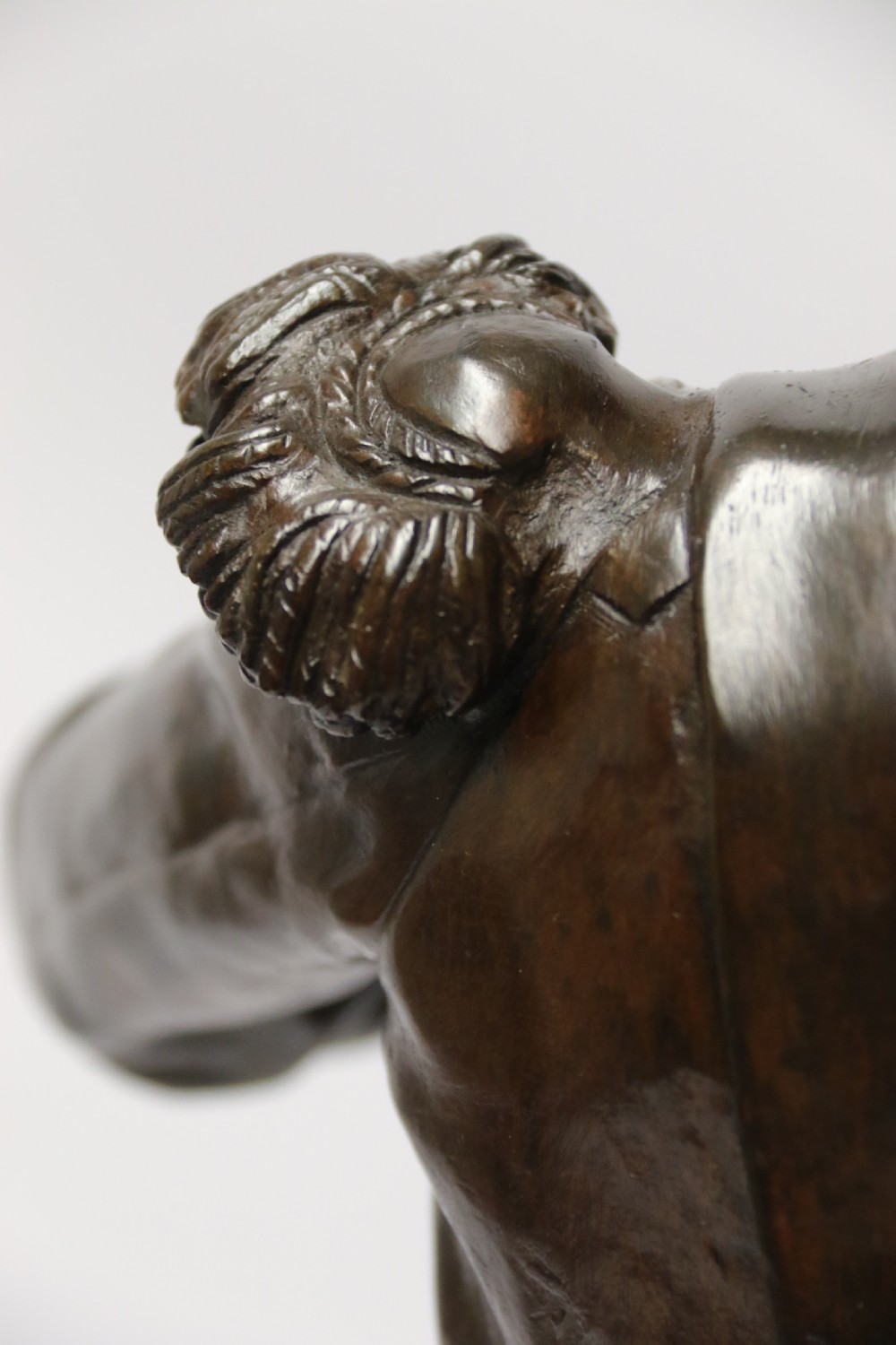 A dark brown patinated bronze sculpture depicting a 1792 French grenadier soldier in full uniform lighting a pipe beside a rifle. View XIV