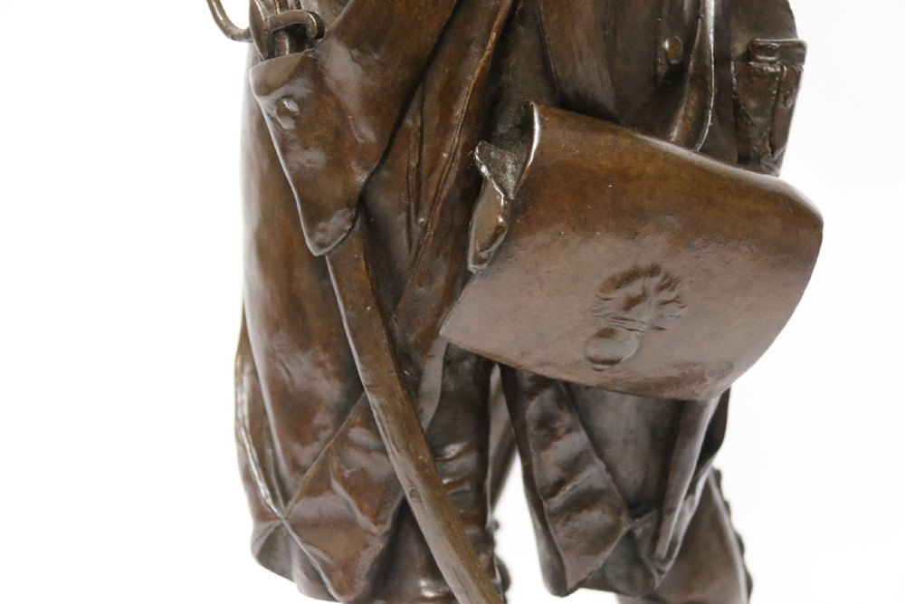 A dark brown patinated bronze sculpture depicting a 1792 French grenadier soldier in full uniform lighting a pipe beside a rifle. View XVI