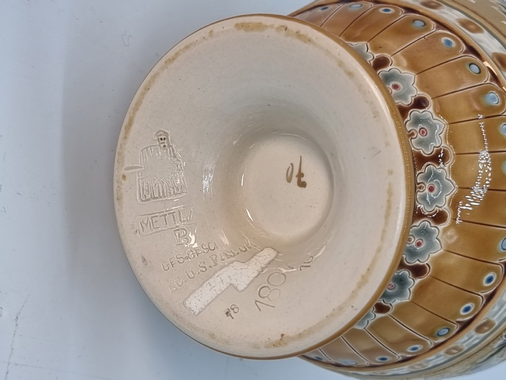 A matching pair of 19th-century German stoneware vases featuring textured tan bodies and incised floral enamel motifs in green, blue, and brown. View XIII