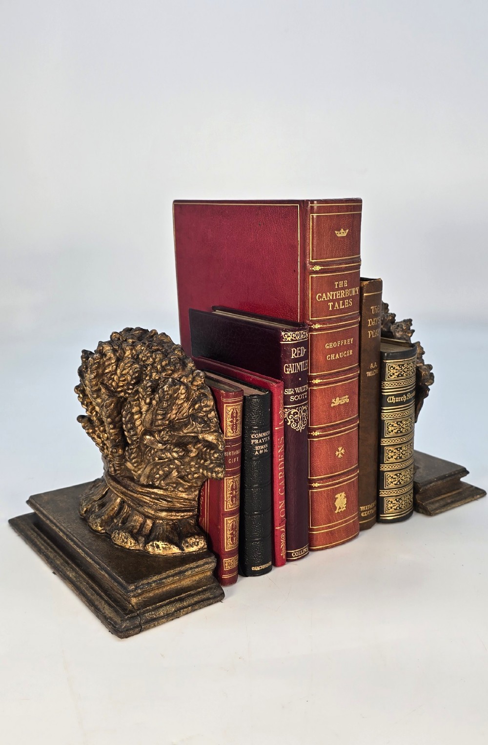 A pair of antique Regency period bookends featuring detailed sculpted wheat sheaves with a gilded finish mounted on stepped bases.