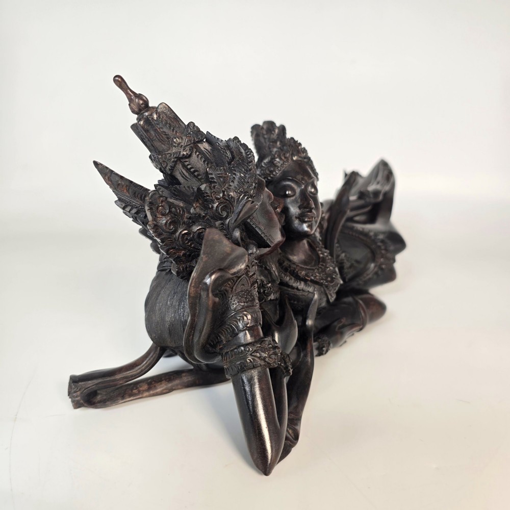 A dark hardwood Balinese carving depicting the reclining figures of Rama and Sita with detailed ornate headdresses and traditional attire. View III