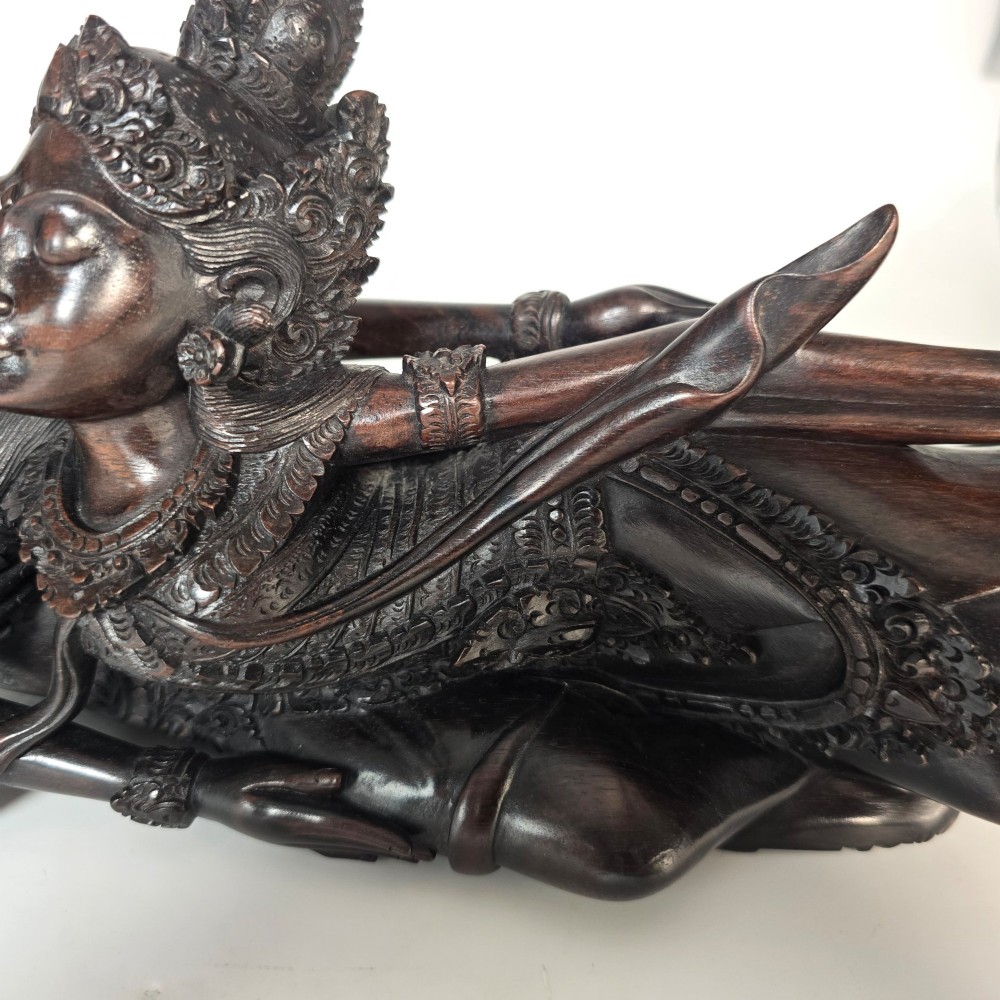 A dark hardwood Balinese carving depicting the reclining figures of Rama and Sita with detailed ornate headdresses and traditional attire. View XIII