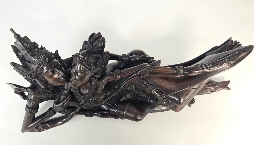 A dark hardwood Balinese carving depicting the reclining figures of Rama and Sita with detailed ornate headdresses and traditional attire. View XV