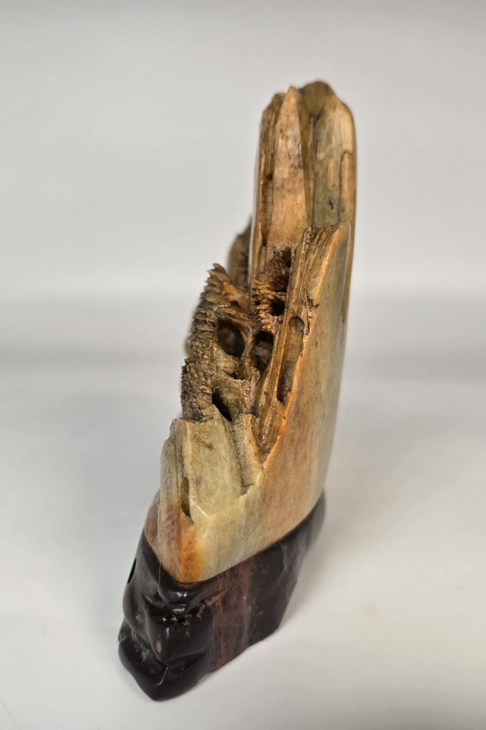 A carved Chinese soapstone continuous landscape featuring mountain peaks, pine trees, and pavilions set upon a fitted dark carved hardwood stand. View V