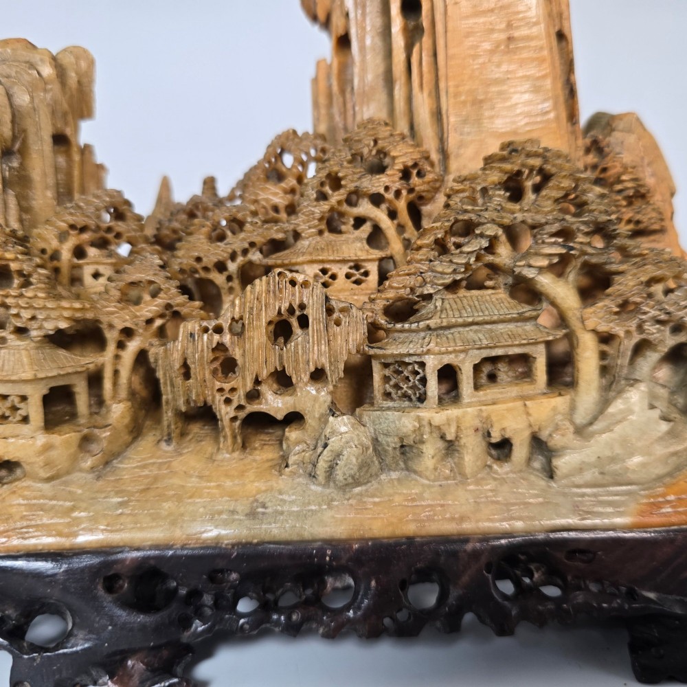 A carved Chinese soapstone continuous landscape featuring mountain peaks, pine trees, and pavilions set upon a fitted dark carved hardwood stand. View VIII
