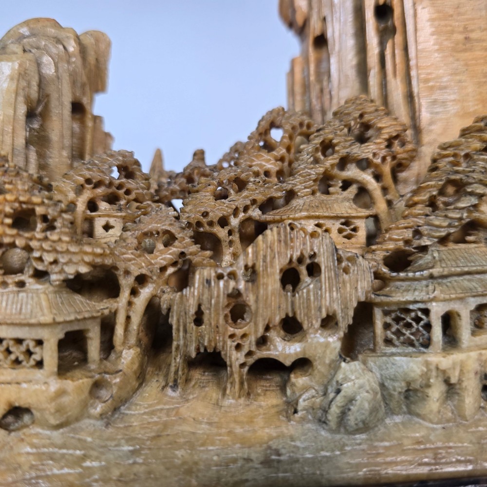A carved Chinese soapstone continuous landscape featuring mountain peaks, pine trees, and pavilions set upon a fitted dark carved hardwood stand. View XII