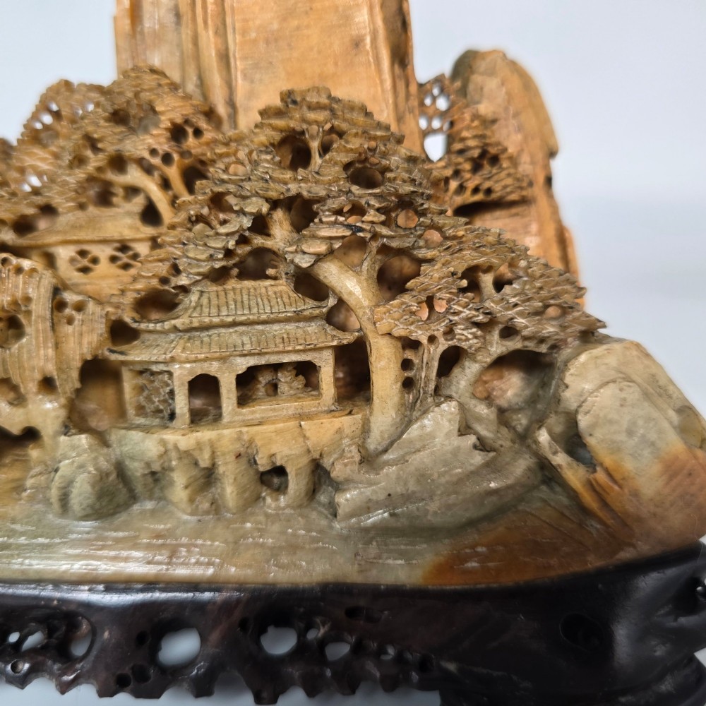 A carved Chinese soapstone continuous landscape featuring mountain peaks, pine trees, and pavilions set upon a fitted dark carved hardwood stand. View XIII