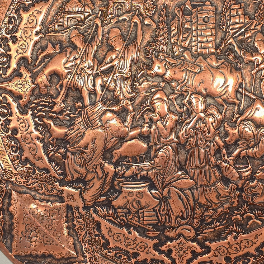 A circular Persian copper charger featuring detailed central repousse relief surrounded by intricate arabesque and paisley borders. View II