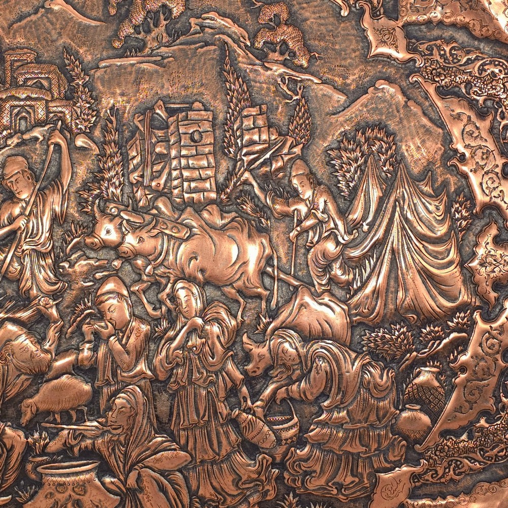 A circular Persian copper charger featuring detailed central repousse relief surrounded by intricate arabesque and paisley borders. View III