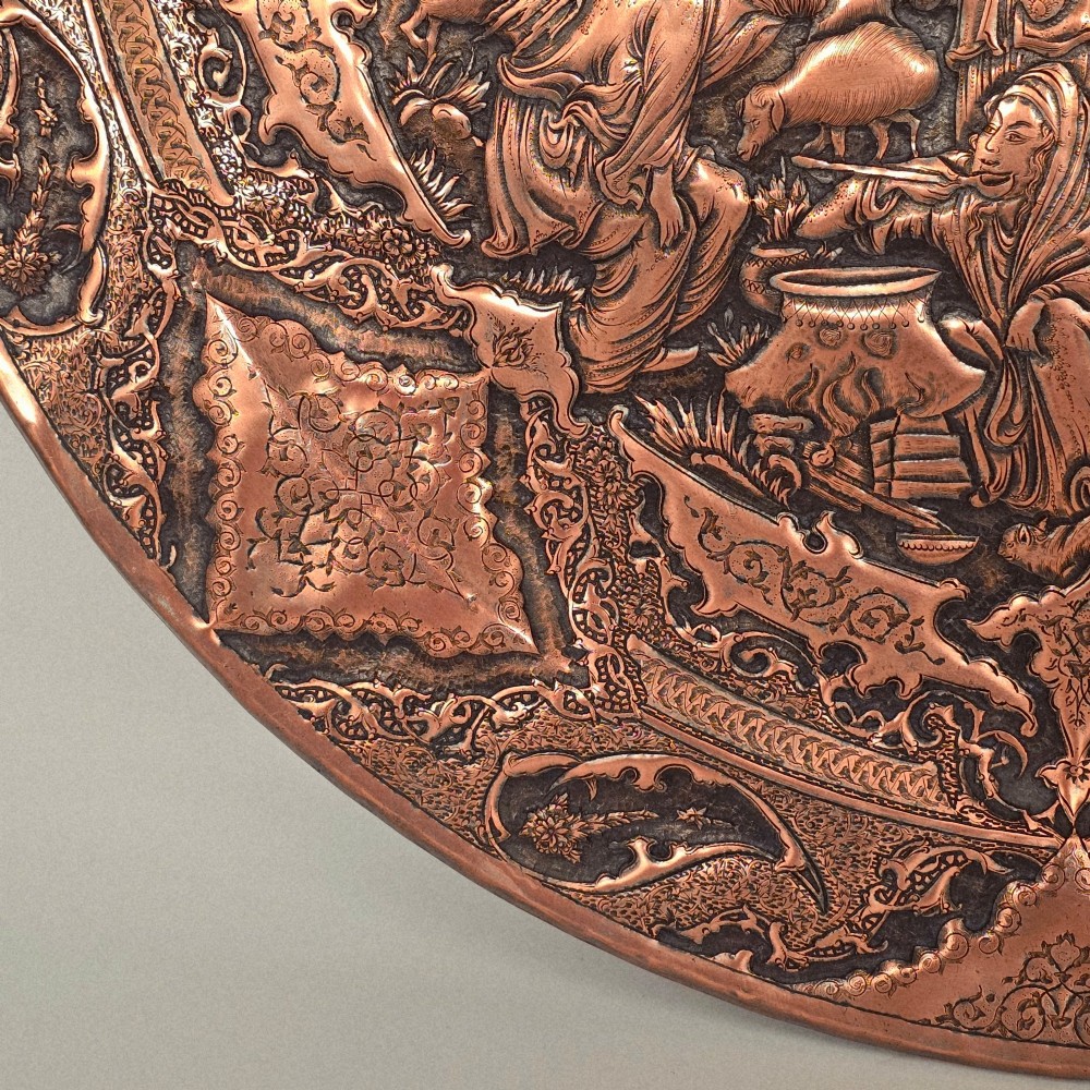 A circular Persian copper charger featuring detailed central repousse relief surrounded by intricate arabesque and paisley borders. View VIII
