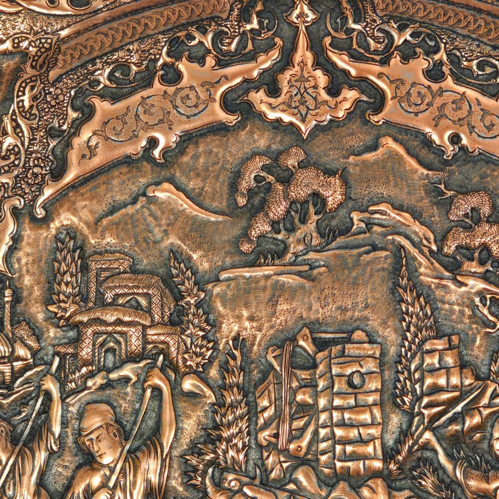 A circular Persian copper charger featuring detailed central repousse relief surrounded by intricate arabesque and paisley borders. View XI