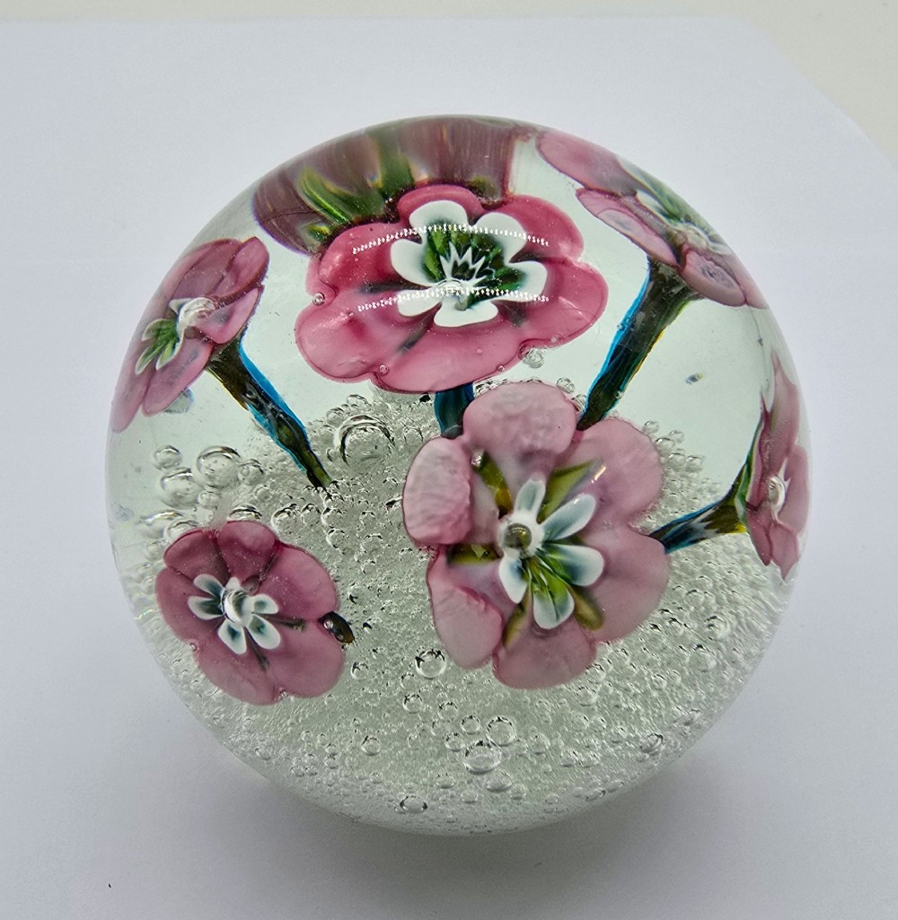 A pair of spherical clear glass paperweights containing pink lampwork flowers above a white bubble base layer. View III