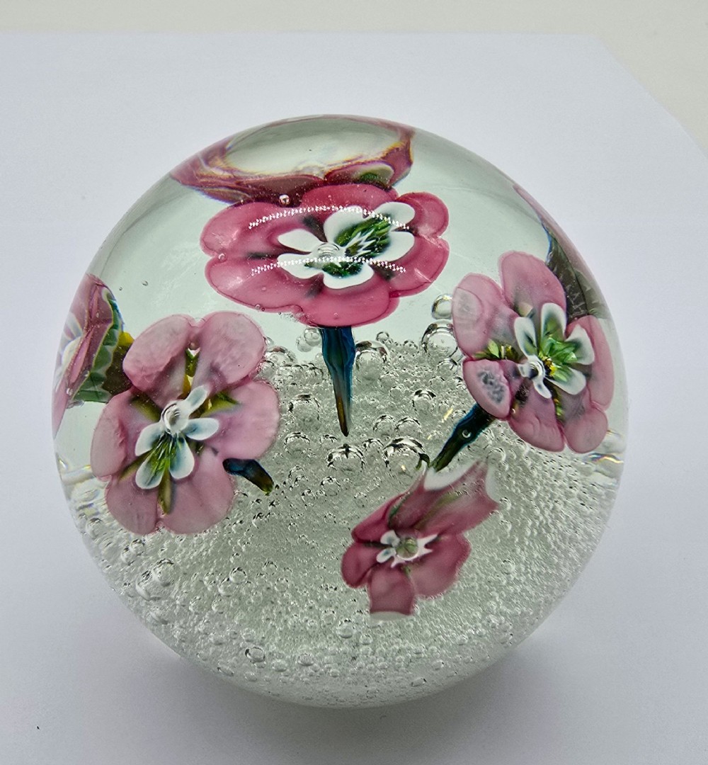 A pair of spherical clear glass paperweights containing pink lampwork flowers above a white bubble base layer. View IV