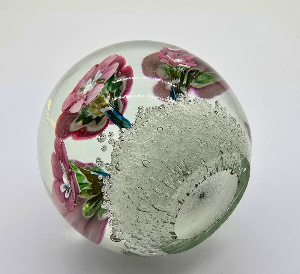 A pair of spherical clear glass paperweights containing pink lampwork flowers above a white bubble base layer. View VI