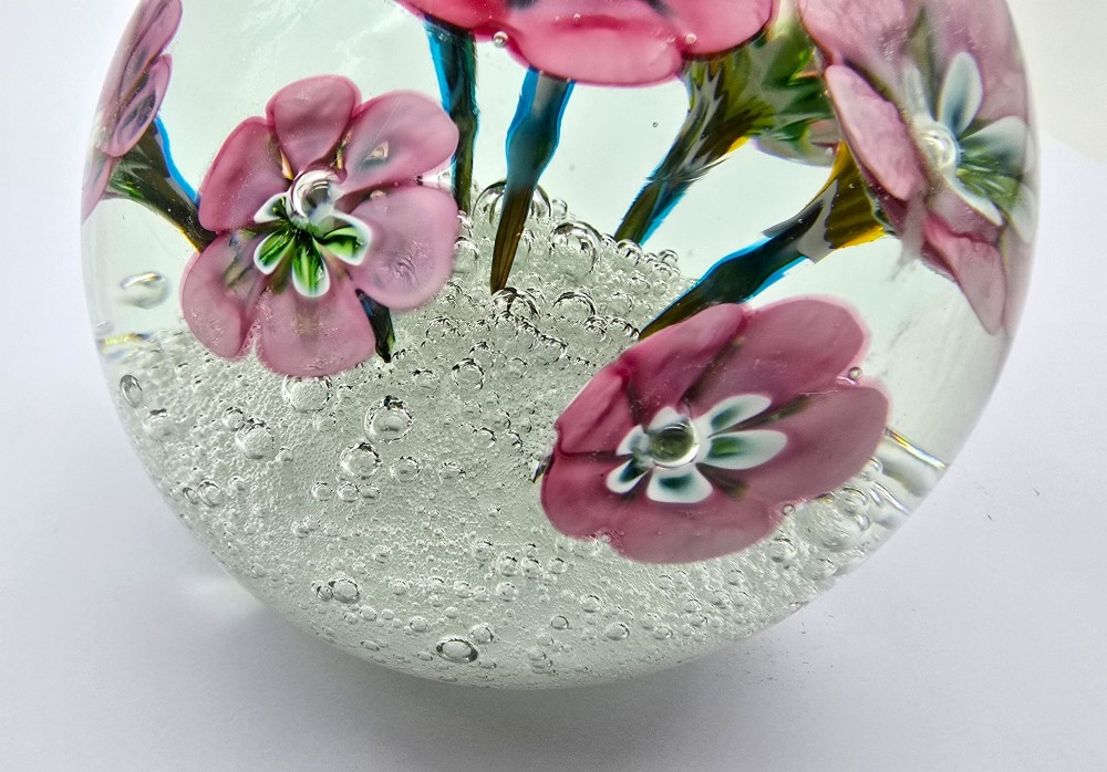 A pair of spherical clear glass paperweights containing pink lampwork flowers above a white bubble base layer. View IX