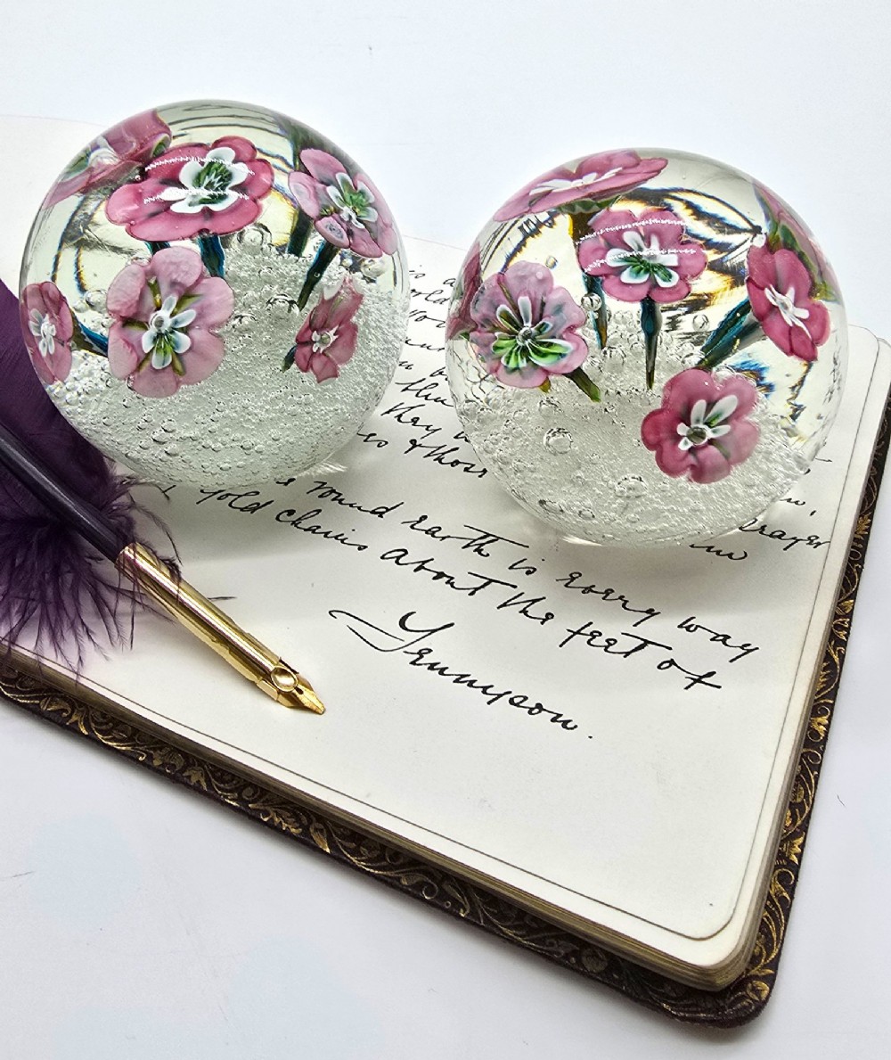 A pair of spherical clear glass paperweights containing pink lampwork flowers above a white bubble base layer. View XIII