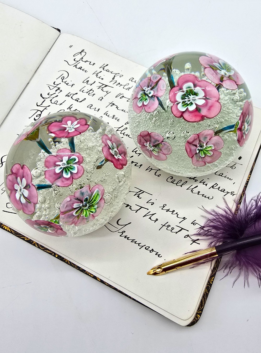 A pair of spherical clear glass paperweights containing pink lampwork flowers above a white bubble base layer. View XIV