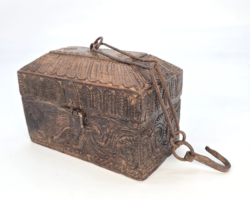 An 18th-century Indian carved dark teak wood spice box featuring a domed lid and attached hand-forged iron hanging chain.