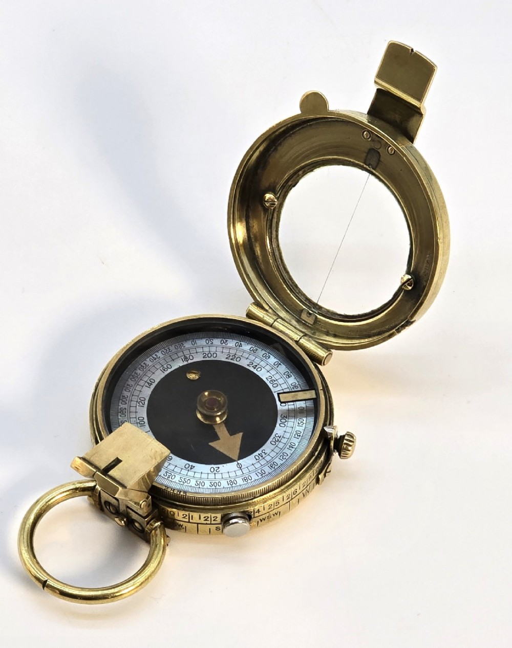 An antique Edwardian brass pocket compass with an open hinged lid featuring a glass window, an engraved internal dial, and an attached thumb ring. View IV