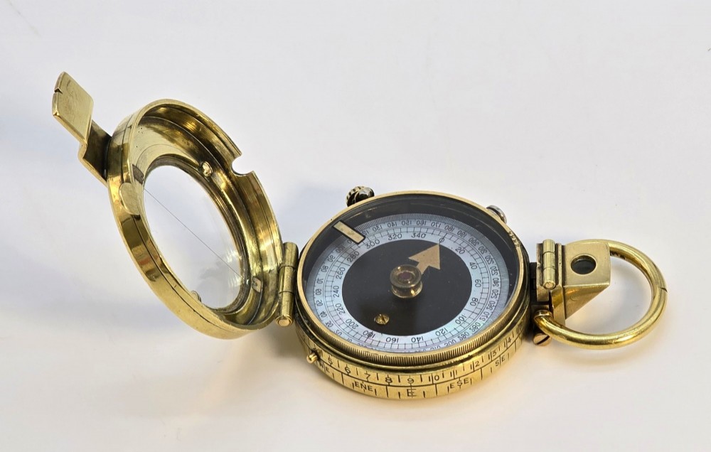 An antique Edwardian brass pocket compass with an open hinged lid featuring a glass window, an engraved internal dial, and an attached thumb ring. View V