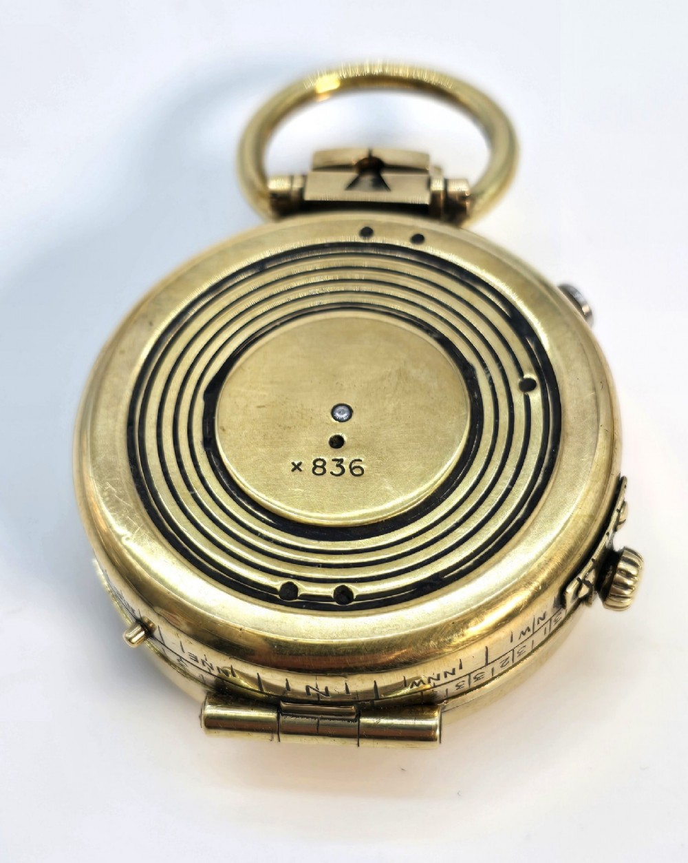 An antique Edwardian brass pocket compass with an open hinged lid featuring a glass window, an engraved internal dial, and an attached thumb ring. View XIII