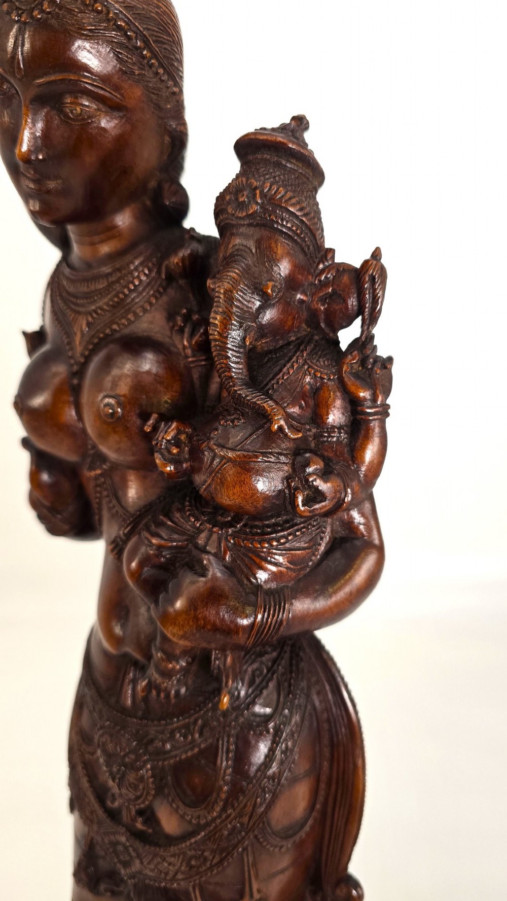 A hand-carved dark wood statue depicting the Goddess Parvati holding infant Ganesha, mounted on an octagonal wooden base. View III