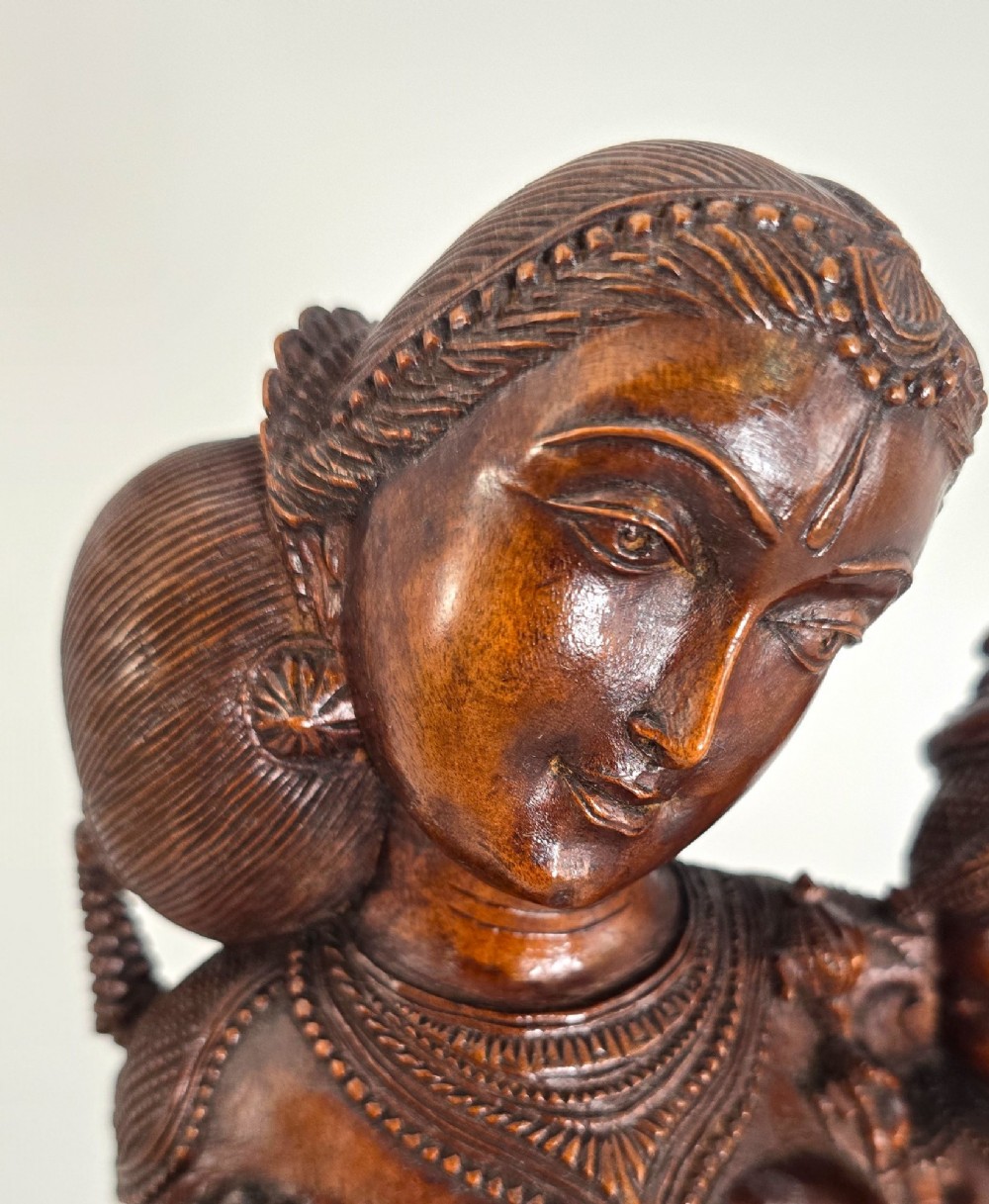 A hand-carved dark wood statue depicting the Goddess Parvati holding infant Ganesha, mounted on an octagonal wooden base. View IV