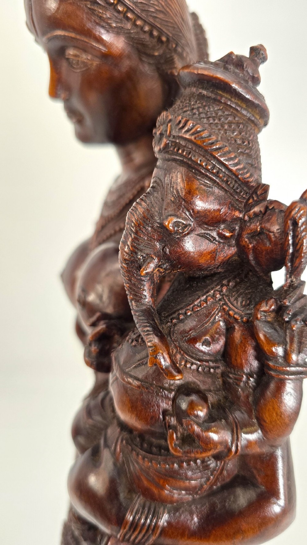 A hand-carved dark wood statue depicting the Goddess Parvati holding infant Ganesha, mounted on an octagonal wooden base. View XV