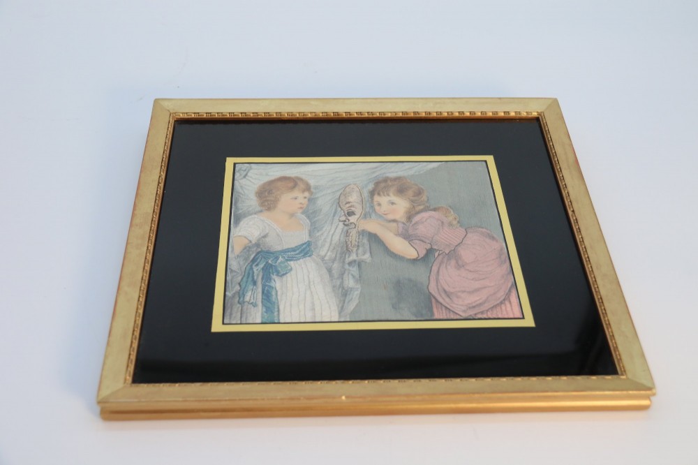 A framed Georgian silk needlework picture depicting two young children with a mask, mounted in a black eglomise frame with gold leaf detailing. View XIII