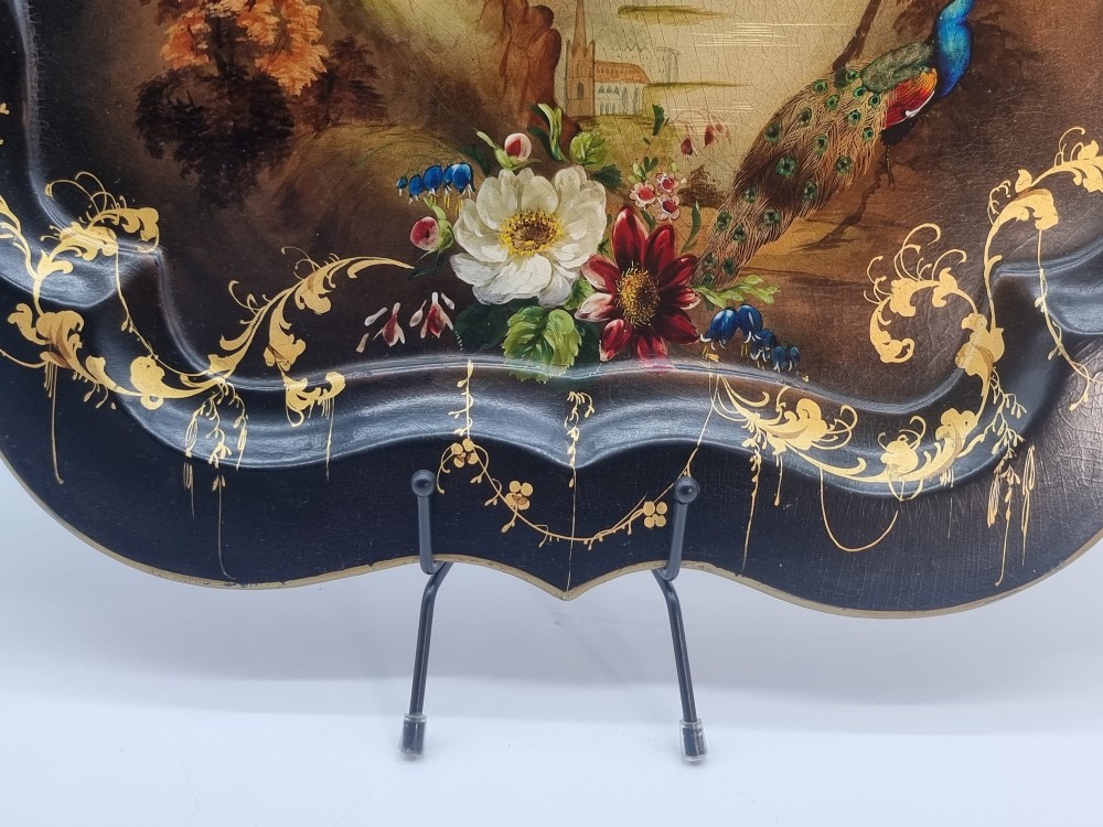 A Victorian shaped papier-mache tray featuring a hand-painted landscape with a castle and peacock surrounded by gold leaf scrollwork on a black background. View IX
