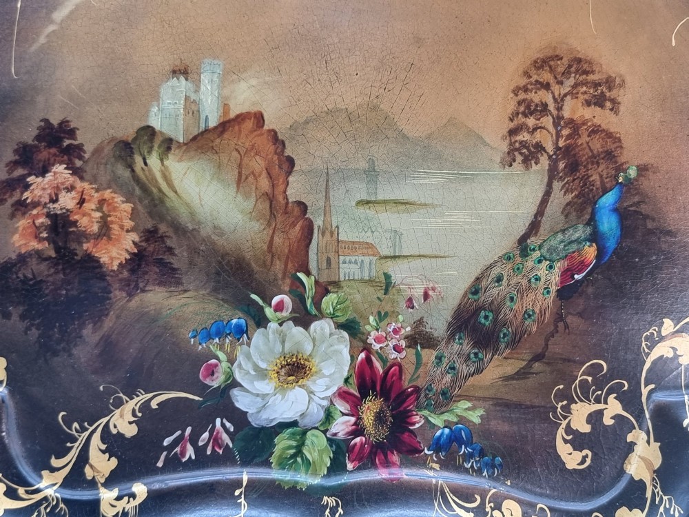 A Victorian shaped papier-mache tray featuring a hand-painted landscape with a castle and peacock surrounded by gold leaf scrollwork on a black background. View X
