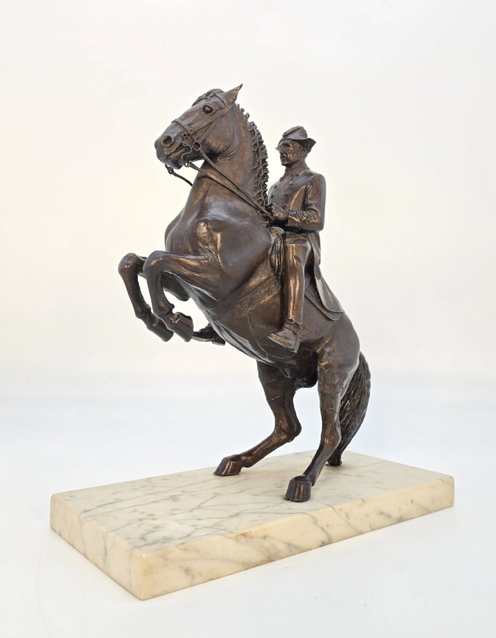 A dark bronze equestrian sculpture depicting a uniformed rider atop a rearing horse, mounted on a rectangular cream marble plinth. View IV