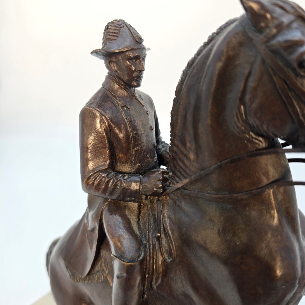A dark bronze equestrian sculpture depicting a uniformed rider atop a rearing horse, mounted on a rectangular cream marble plinth. View XI