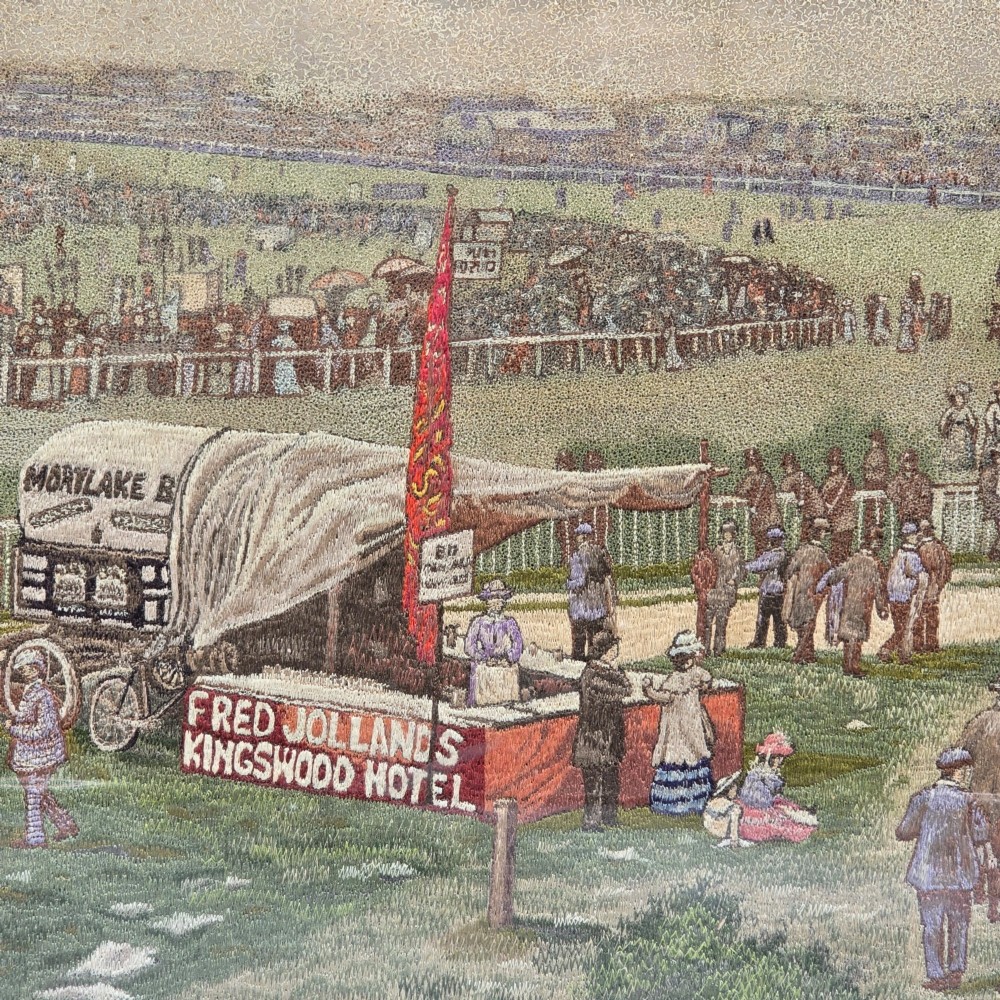 A framed rectangular silk needlework picture depicting figures gathered at the Epsom racecourse within an ornate gilded frame. View II