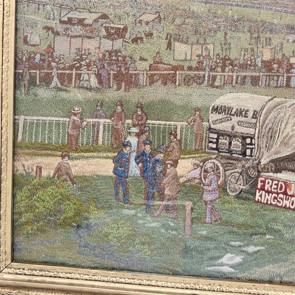 A framed rectangular silk needlework picture depicting figures gathered at the Epsom racecourse within an ornate gilded frame. View IV