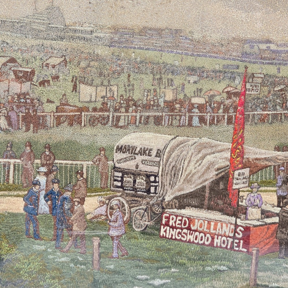 A framed rectangular silk needlework picture depicting figures gathered at the Epsom racecourse within an ornate gilded frame. View V