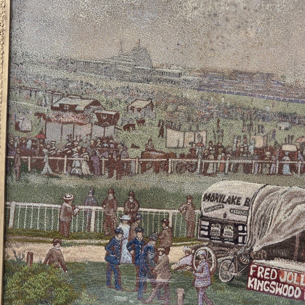 A framed rectangular silk needlework picture depicting figures gathered at the Epsom racecourse within an ornate gilded frame. View VI