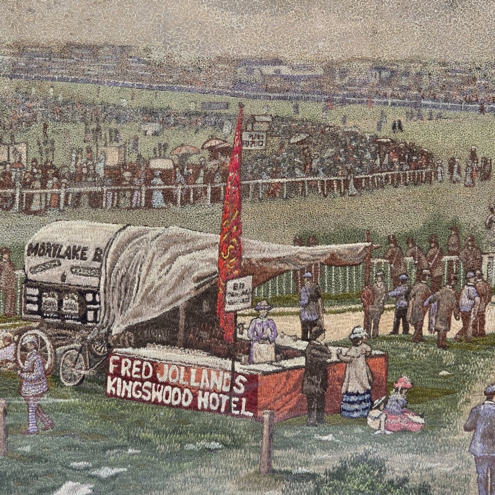 A framed rectangular silk needlework picture depicting figures gathered at the Epsom racecourse within an ornate gilded frame. View VII