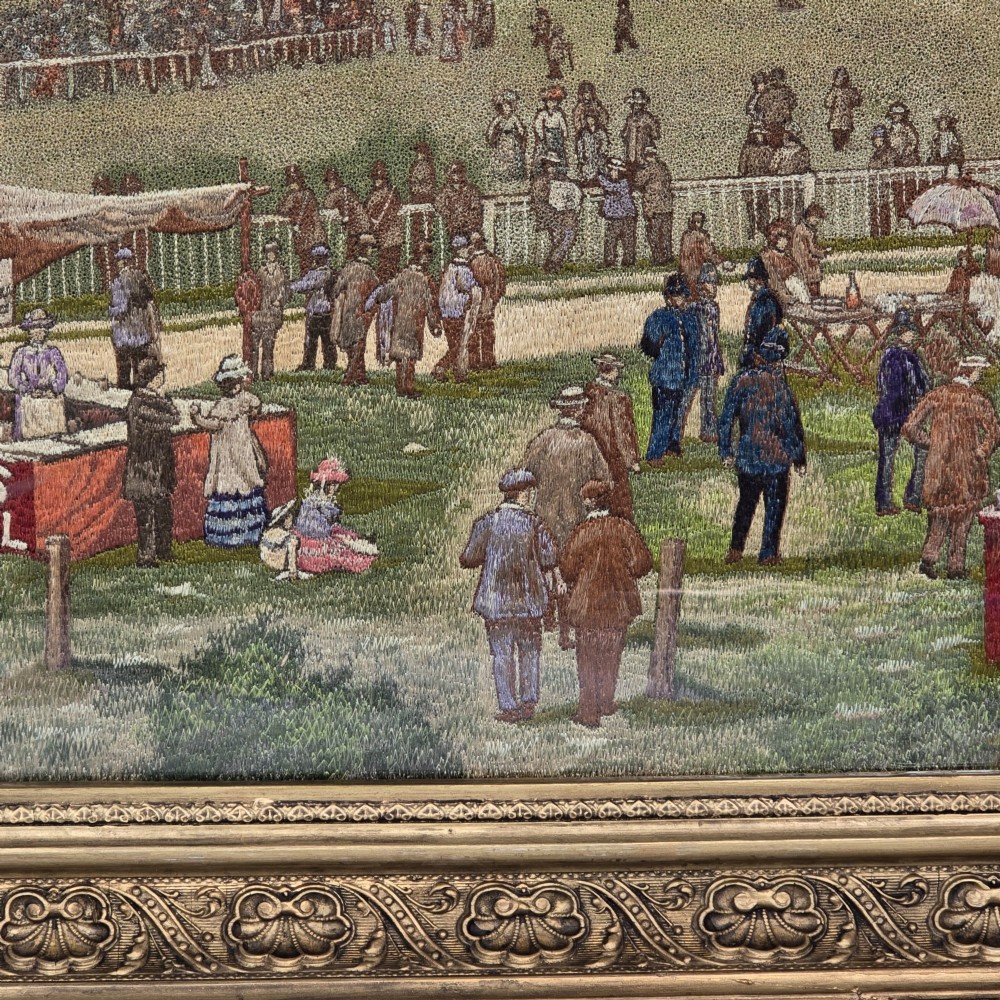 A framed rectangular silk needlework picture depicting figures gathered at the Epsom racecourse within an ornate gilded frame. View VIII