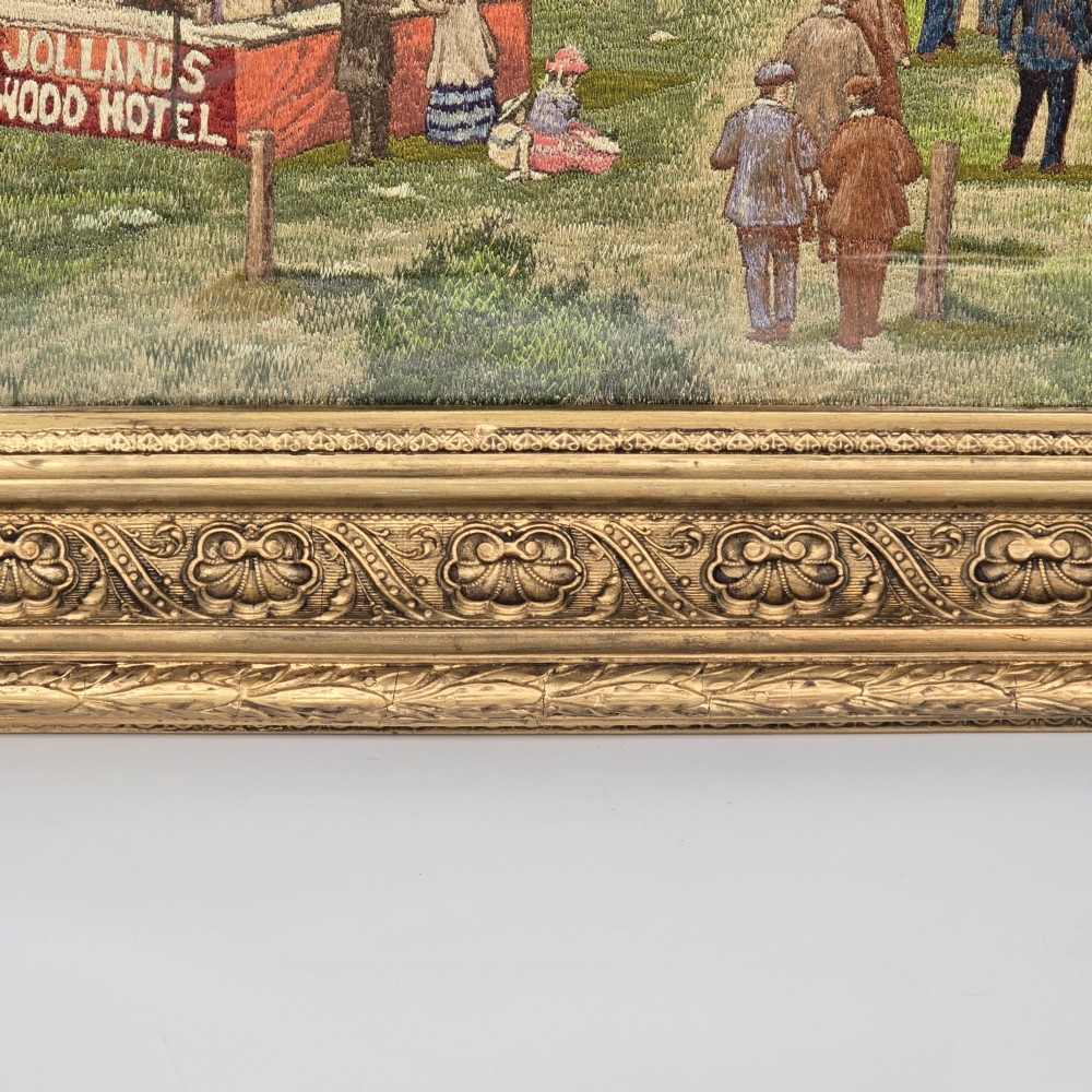 A framed rectangular silk needlework picture depicting figures gathered at the Epsom racecourse within an ornate gilded frame. View IX